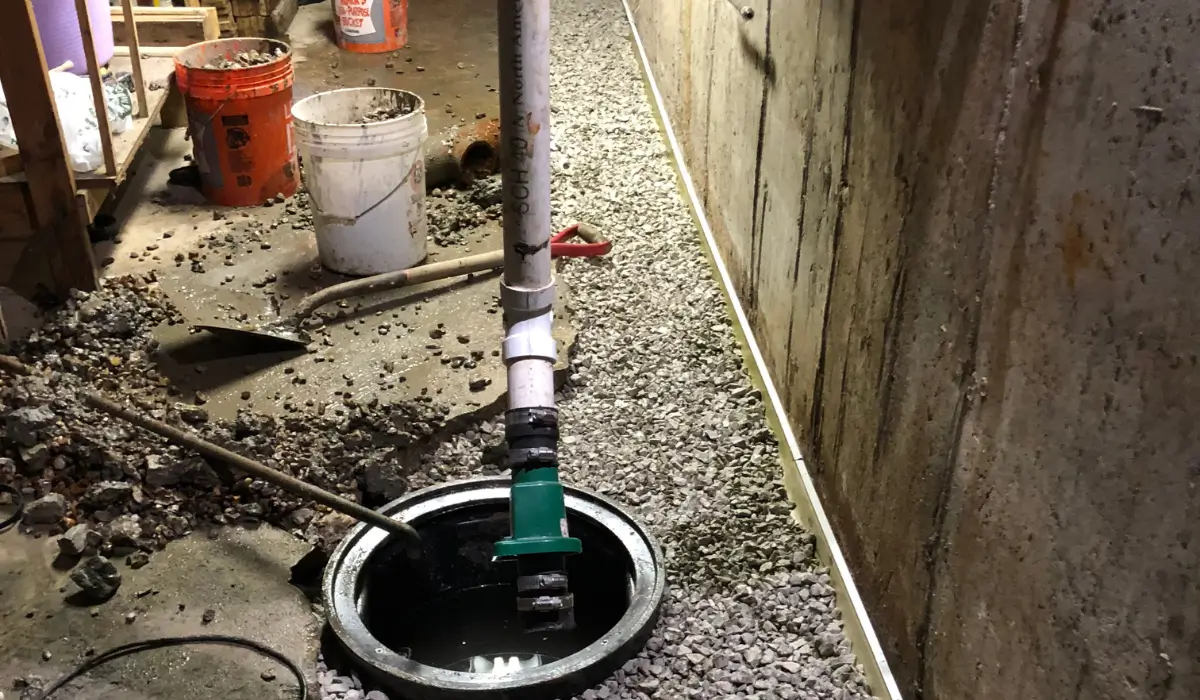 Basement sump pit during sump pump repair or replacement, showing active system components installed to reduce sump pump failure.